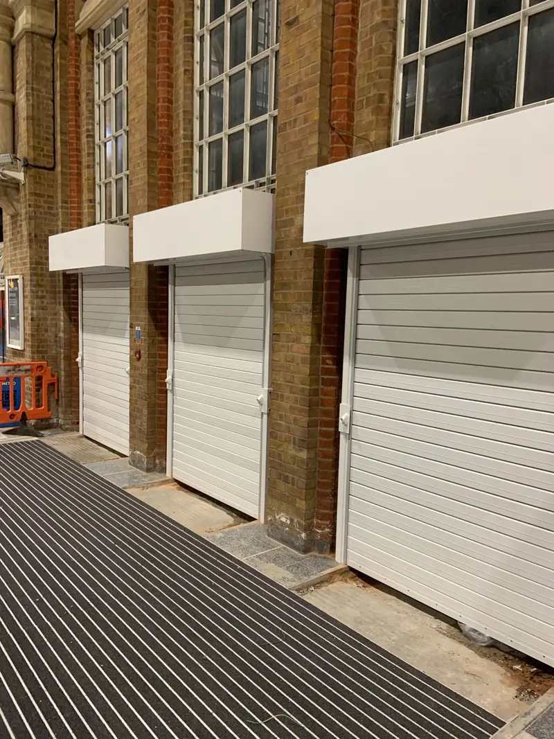 white roller shutters fitted in the arches, one per opening.