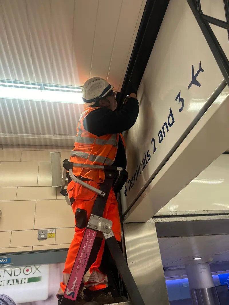 Engineers on ladders fitting collapsible grilles on a station concourse
